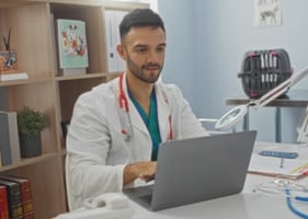 A vet sits at a laptop considering veterinary postgraduate training