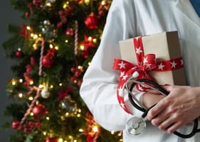 A vet with coat and stethoscope holding a Christmas present